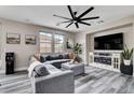 Relaxing living room featuring a sectional sofa, decorative fireplace, sleek ceiling fan, and views of the backyard at 688 Monument Point St, Henderson, NV 89002