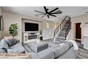 Comfortable living room with modern decor, a large ceiling fan, fireplace, and staircase to the upper level at 688 Monument Point St, Henderson, NV 89002