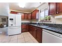 Cozy kitchen featuring dark wood cabinets, granite countertops and modern white appliances at 704 N Wallace Dr, Las Vegas, NV 89107