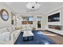 Bright living room with modern lighting, a fireplace, a large window, and a comfortable white sectional sofa at 8353 Lower Trailhead Ave, Las Vegas, NV 89113