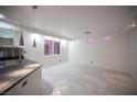 Bright living room featuring tile floors, modern lighting, and an adjacent kitchen area at 10414 Midseason Mist St, Las Vegas, NV 89183