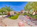 A landscaped front yard of a single-story home features stone accents and green artificial turf at 2205 Sandstone Cliffs Dr, Henderson, NV 89044