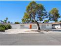 Charming single-story home featuring a white facade, orange front door and mature landscaping at 2245 Sombrero Dr, Las Vegas, NV 89169