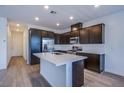 Modern kitchen with stainless steel appliances, dark cabinets, and a quartz island countertop at 31 Newport Edge Pl, Henderson, NV 89015