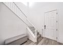 Inviting entryway with a staircase, gray wood flooring, white wall paint, and a storage bench at 3821 Nesting Wren Dr, North Las Vegas, NV 89084