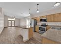 Bright kitchen featuring an island, stainless steel appliances, wood cabinets, and open layout to the living area at 5001 Morning Falls Ave, Las Vegas, NV 89131