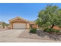 Tan single-story house featuring desert landscaping, a spacious driveway, and an attached garage at 10428 Villa Ridge Dr, Las Vegas, NV 89134