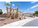 A view of the home's side and front, showcasing the desert landscaping, palm trees and spacious driveway at 8824 Killians Greens Dr, Las Vegas, NV 89131