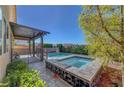 The outdoor space features a stone-trimmed spa, complemented by lush greenery at 9542 Ridgeglen Ct, Las Vegas, NV 89148