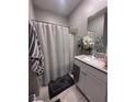 Cozy bathroom featuring a shower with curtain, neutral-colored walls, decorative mirror and vanity with a white cabinet at 10163 Kings Amethyst St, Las Vegas, NV 89141