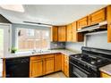 A well-lit kitchen features wood cabinets, granite counters, black appliances, and a large window overlooking the backyard at 1480 Hialeah Dr # B, Las Vegas, NV 89119