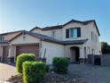 Side view of a tan two story home with a three car garage and low maintenance landscaping at 4076 Topaz Hills Dr, North Las Vegas, NV 89032