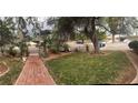 Landscaped front yard with lush grass, mature trees, and a brick walkway at 4444 Denia Cir, Las Vegas, NV 89108