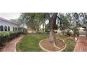 Beautifully landscaped front yard with mature trees, brick walkway, and well-maintained hedges at 4444 Denia Cir, Las Vegas, NV 89108