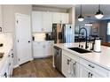 Kitchen area with island, white cabinets, stainless appliances, and wood flooring at 8186 Guadiano Ave, Las Vegas, NV 89113