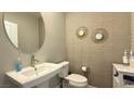 Stylish powder room featuring modern fixtures, pedestal sink, round mirror, and decorative wallpaper for guests at 9136 Eagle Ford St, Las Vegas, NV 89113