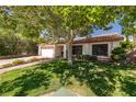 Serene single-story home with mature trees, a red tile roof, and lush green lawn at 2821 Whispering Wind Dr, Las Vegas, NV 89117