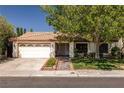 Single-story home featuring a red tile roof, mature landscaping, and a welcoming entrance at 2821 Whispering Wind Dr, Las Vegas, NV 89117