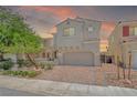 Charming two-story home at sunset with a paver driveway and low-maintenance desert landscaping at 1000 Cetona Ct, Henderson, NV 89011