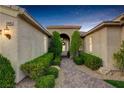 Charming home showcasing a paved walkway leading to an arched entryway, framed by lush landscaping and mature trees at 10400 Premia Pl, Las Vegas, NV 89135