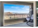 Balcony view with egg chair overlooking cityscape and mountains under a bright sky at 11658 Midnight Melody Ave, Las Vegas, NV 89138