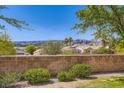 Private backyard featuring a brick wall, lush greenery, and views of distant mountains at 2085 Joy View Ln, Henderson, NV 89012
