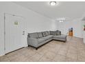 Bright living room featuring neutral tile flooring and a comfortable gray couch at 6868 Sky Pointe Dr # 1107, Las Vegas, NV 89131