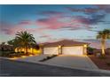 Home exterior featuring an attached three-car garage, desert landscaping and a well-maintained lawn at 8650 W Verde Way, Las Vegas, NV 89149