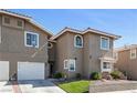 Inviting exterior view of a townhome showcases a two-car garage, neat landscaping, and classic architectural details at 9270 Apache Springs Dr, Las Vegas, NV 89117