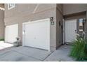 Welcoming entrance to a townhome features a two-car garage and a nicely landscaped walkway to the front door at 9270 Apache Springs Dr, Las Vegas, NV 89117