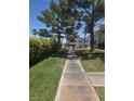 A pathway leading to a condo complex with blue awnings, surrounded by lush landscaping and mature trees at 101 Luna Way # 104, Las Vegas, NV 89145