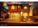 Inviting two-story home at dusk, with a glass garage door and warm lighting at 10342 Kesington Dr, Las Vegas, NV 89135