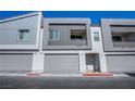 Modern townhome facade shows gray garage doors and neutral color scheme, enhanced curb appeal at 139 Aqua Commons Ln, Henderson, NV 89015