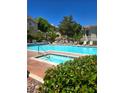 A luxurious pool is surrounded by lounge chairs, mature trees, and a building at 1500 Cardinal Peak Ln # 201, Las Vegas, NV 89144