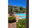 A luxurious pool is surrounded by lounge chairs, mature trees, and a building at 1500 Cardinal Peak Ln # 201, Las Vegas, NV 89144