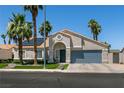 Inviting single-story home showcasing desert landscaping, a blue garage door, and solar panels at 5025 Chambliss Dr, Las Vegas, NV 89130