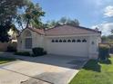 Single-story home featuring a two-car garage, tile roof, and mature landscaping in a well-kept neighborhood at 5401 Painted Sunrise Dr, Las Vegas, NV 89149