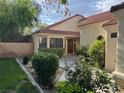 Inviting front entrance with manicured shrubs, brick accents, and a wooden front door at 5401 Painted Sunrise Dr, Las Vegas, NV 89149