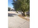 Long driveway leads to the back of the beige house with mature tree on the property at 1936 Lawry Ave, North Las Vegas, NV 89032