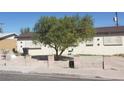 Beige single story home features a tree and security bars over the windows at 1936 Lawry Ave, North Las Vegas, NV 89032
