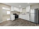 Well-lit kitchen featuring stainless steel appliances, white cabinets, and wood-look flooring at 4676 E Alexander Rd, Las Vegas, NV 89115