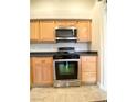 Close up of stainless steel oven and microwave in the kitchen with tiled floors and wooden cabinets at 4717 Mohawk River Ave, North Las Vegas, NV 89031