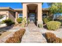 Elegant front entrance showing a brick pathway, desert landscaping, and iron security gate at 5193 N Miller Ln, Las Vegas, NV 89149