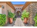 Inviting entryway featuring stone accents, brick pavers, and decorative potted plants enhancing curb appeal at 2509 Chateau Napoleon Dr, Henderson, NV 89044