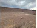 A spacious backyard featuring minimal landscaping and surrounded by a high block wall for privacy and potential at 3237 Perching Bird Ln, North Las Vegas, NV 89084