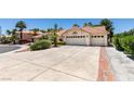 Attractive single-story home with a tile roof, lush landscaping, and a generous driveway leading to a three-car garage at 399 Discovery Ct, Henderson, NV 89014