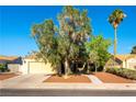 A wide shot of a tan single story home featuring a desert landscape, a driveway, and a two-car garage at 5104 Drummond Rd, Las Vegas, NV 89130