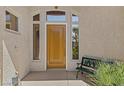 Inviting front entryway with a stylish wood door, sidelight windows, and an ornate bench seat at 613 Via Linda Ct, Las Vegas, NV 89144