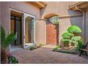 Enclosed front courtyard with tile flooring and lush green bushes creates a private outdoor oasis at 9233 Canyon Mesa Dr, Las Vegas, NV 89144