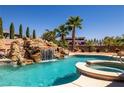Backyard swimming pool featuring rock waterfall, tropical landscaping, and spa at 231 Bristle Cone, Pahrump, NV 89048